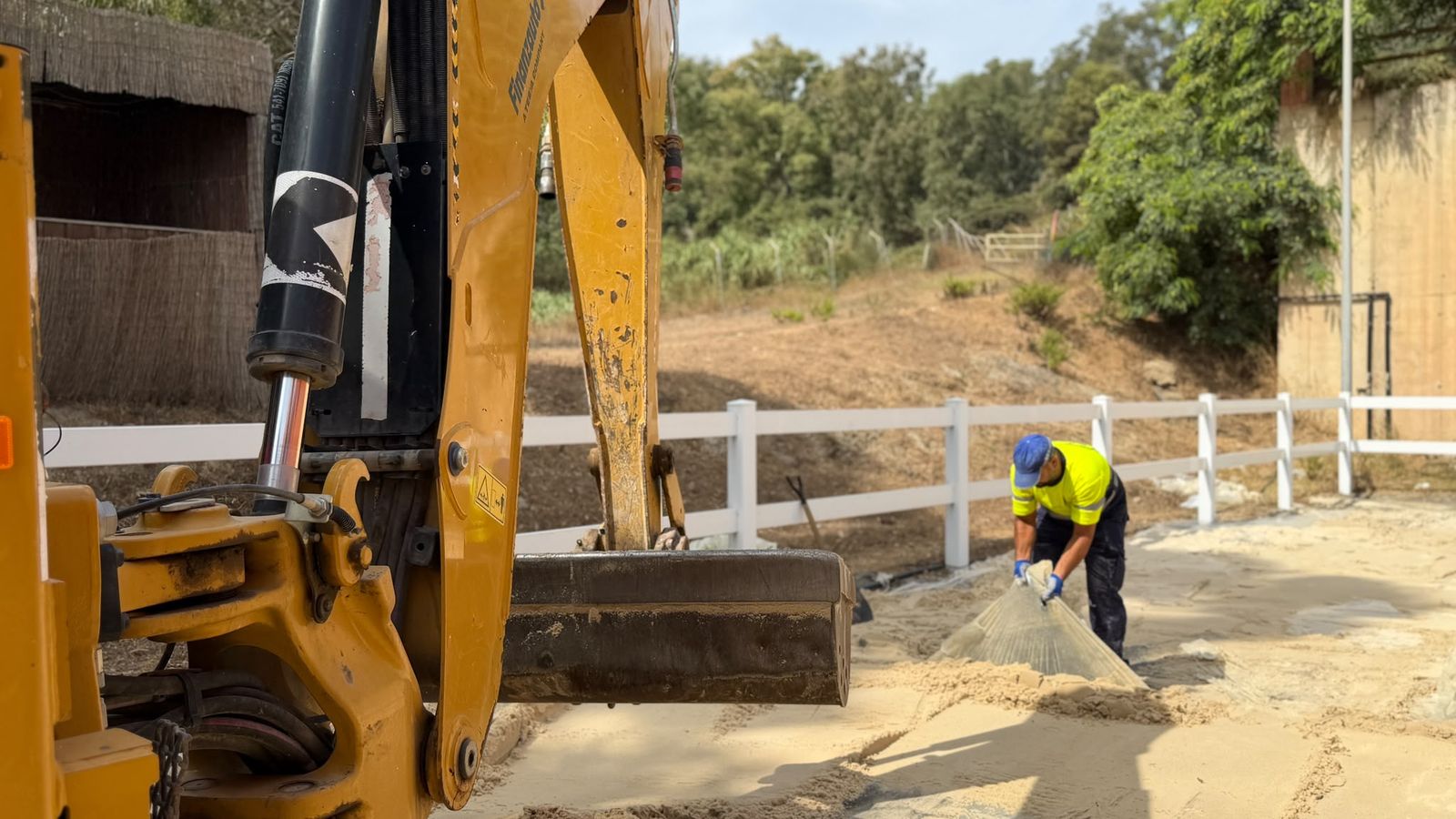 Una excavadora extrae la arena de la pista principal del Centro Ecuestre, donde ubicarán modulares para acoger migrantes