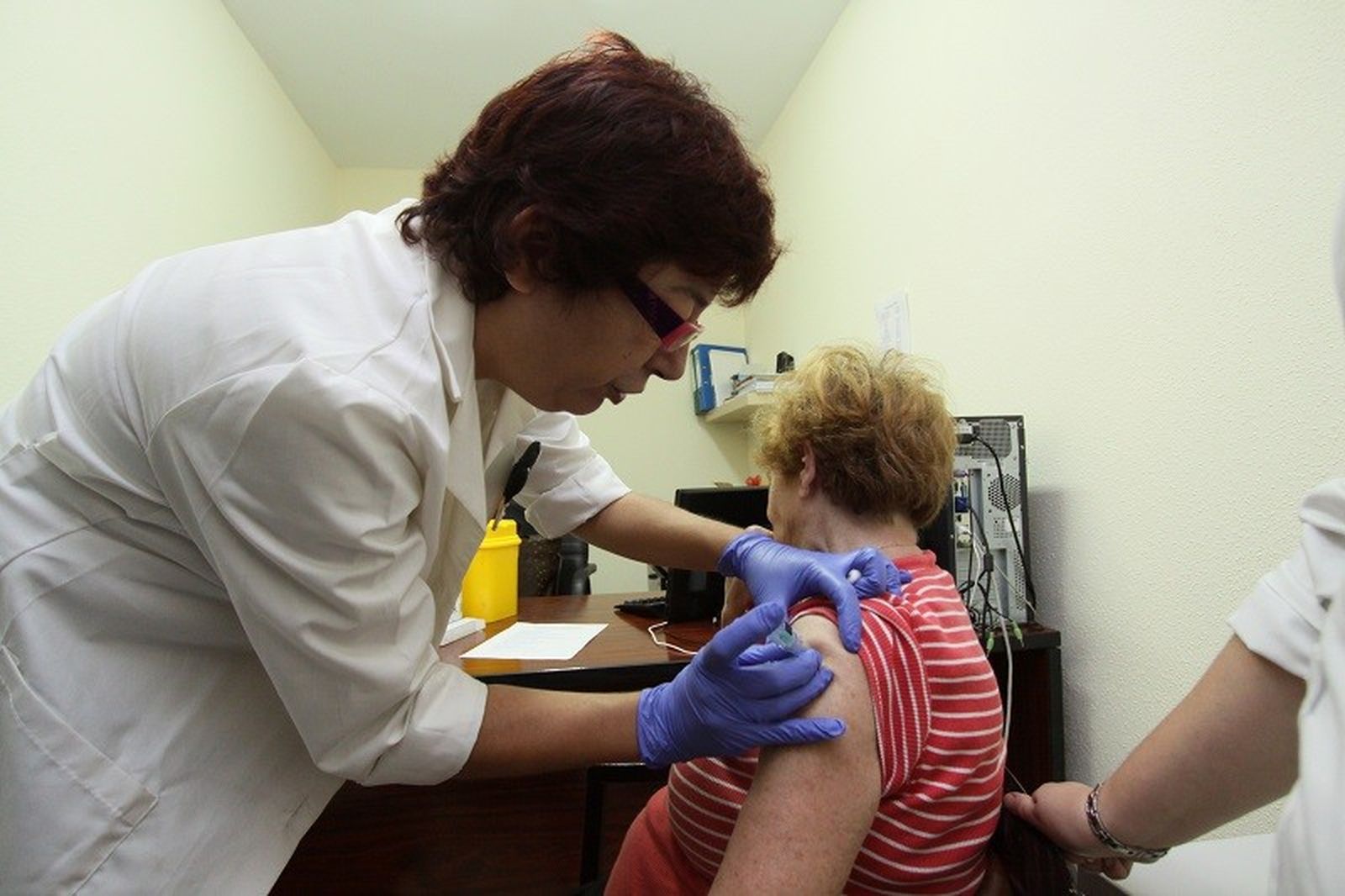 Una enfermera vacunando a una señora de la gripe