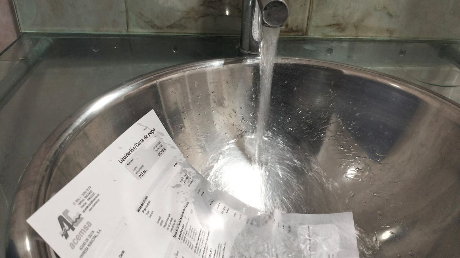 Imagen de una factura con un chorro de agua de un grifo.