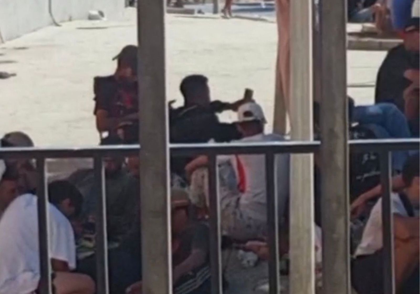 Migrantes varones tendidos en el suelo frente a las ventanas de un bloque de Loma Colmenar