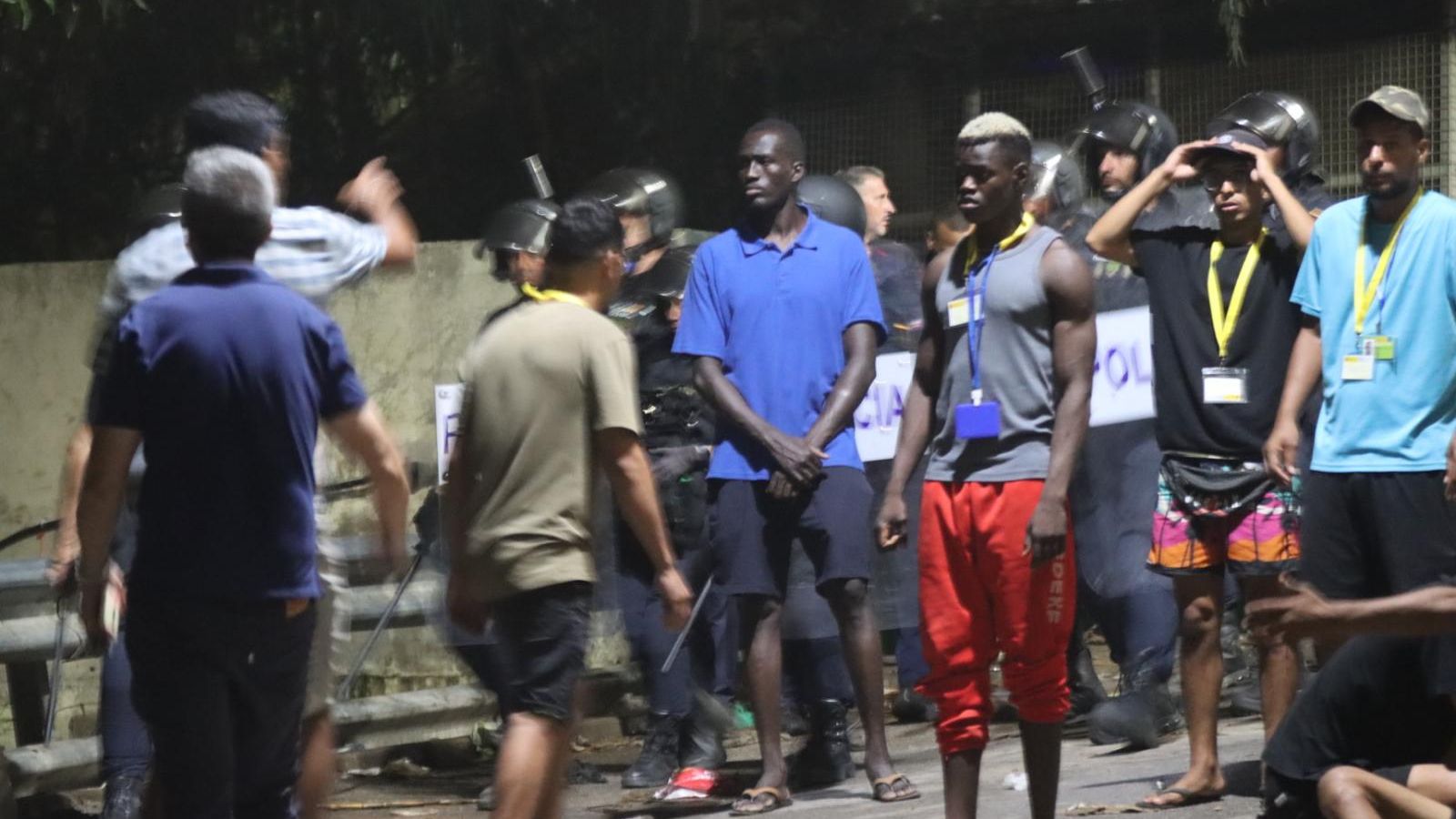Varios migrantes delante del cordón policial que despejó el CETI