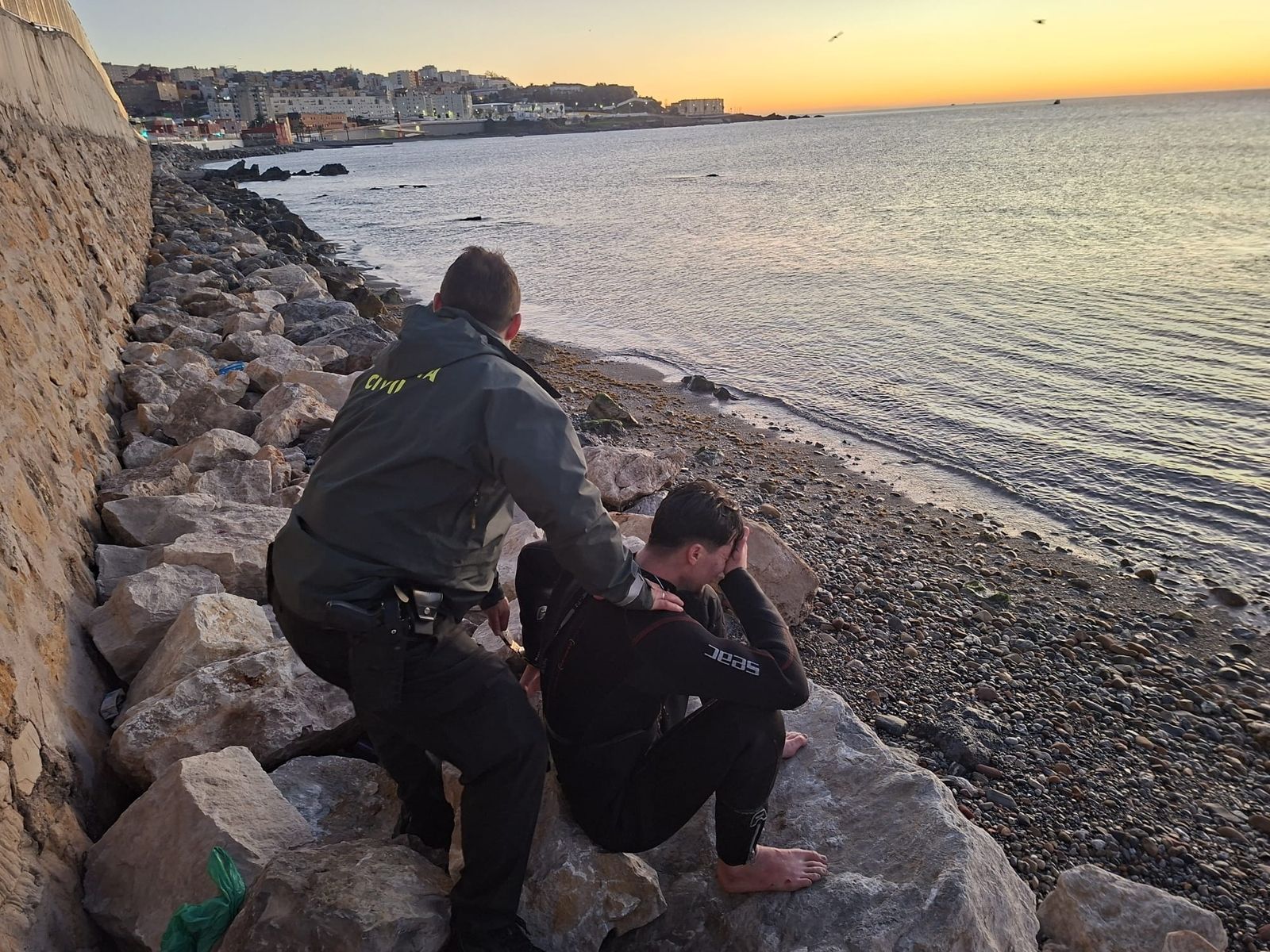 Un guardia civil atiende a un migrante recién llegado a la costa ceutí