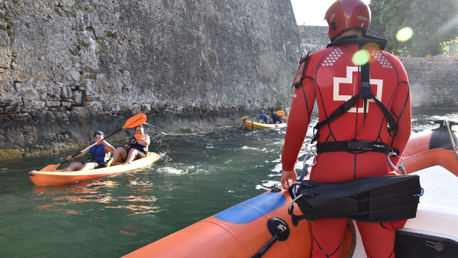 El socorrista José Antonio Carracao saluda a varios usuarios en kayak que transitan el foso de las Murallas Reales. Cuando navegan por la zona suelen advertir del peligro de las corrientes. Aquel día, dos niños situados sobre el Puente de Cristo preguntaron a los voluntarios de Cruz Roja si la zona estaba despejada para saltar. No es la primera vez que viven esa escena