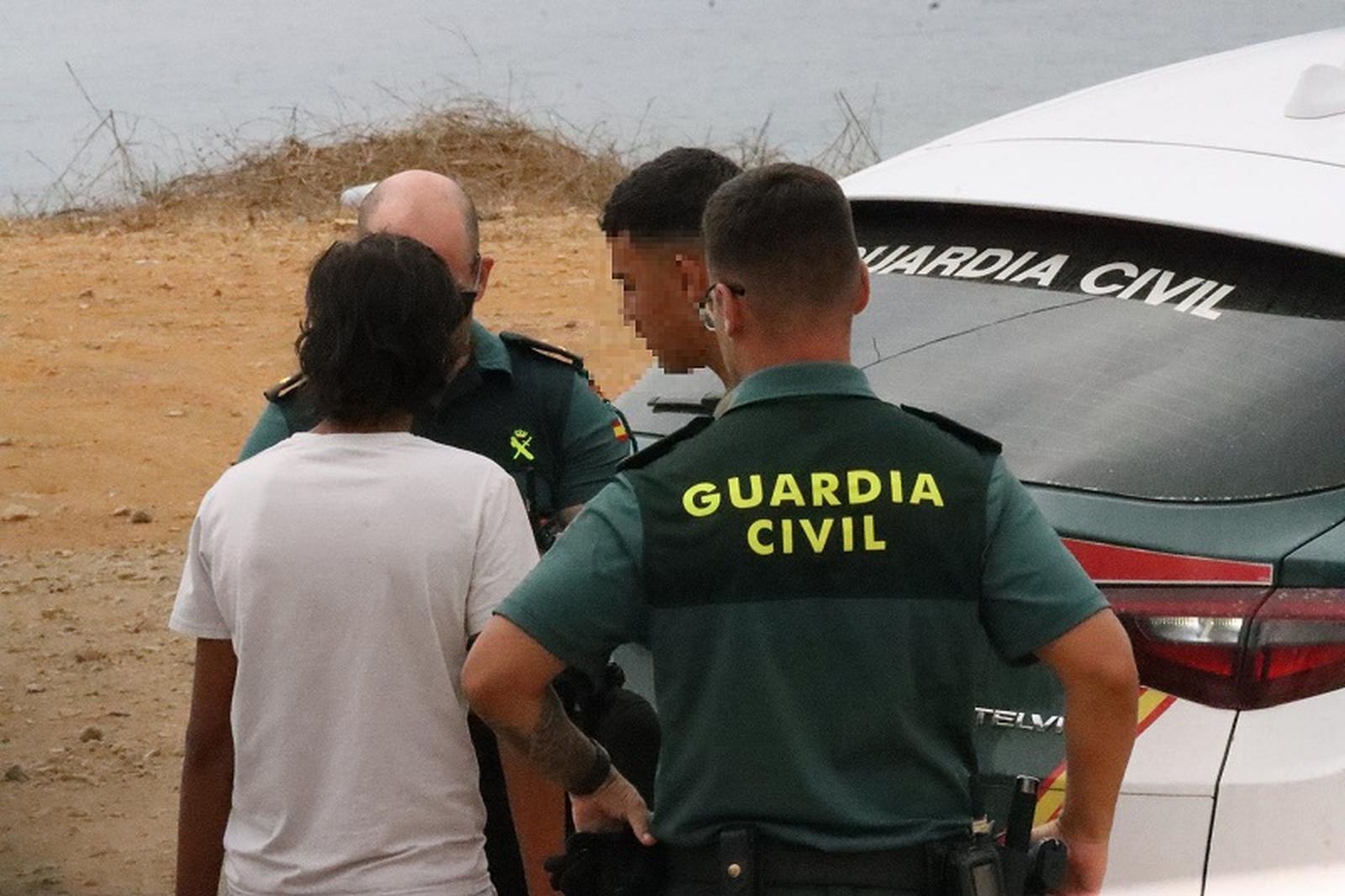 Agentes de la Guardia Civil interrogan a dos menores migrantes que acaban de acceder a Ceuta, este sábado. / FOTO REDUAN