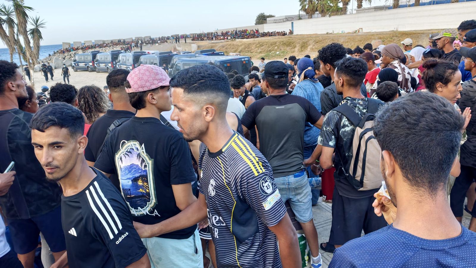 Cruz Roja reparte alimentos a los migrantes que hoy han llegado a la playa del Trampolín mientras la Policía Nacional los coordina