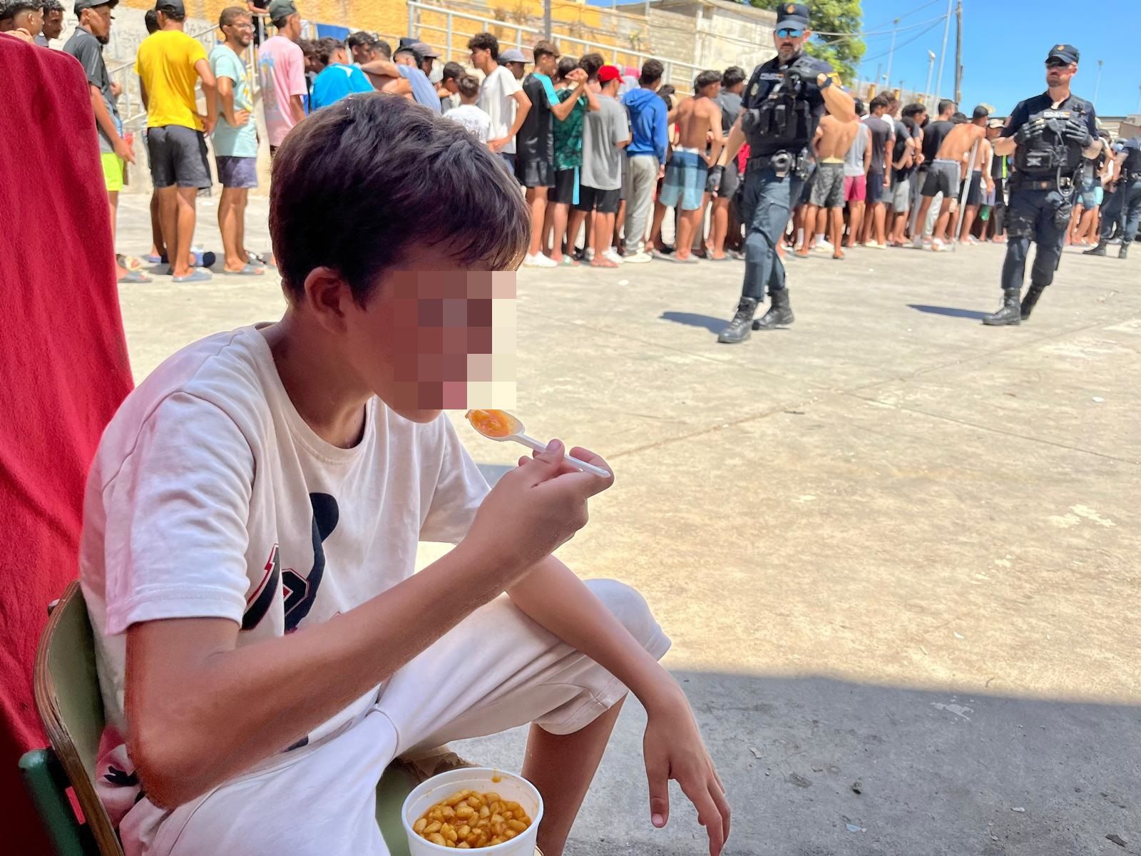 Un chaval recién llegado, en las naves del Tarajal, comiendo alimentos donados por organizaciones sociales.