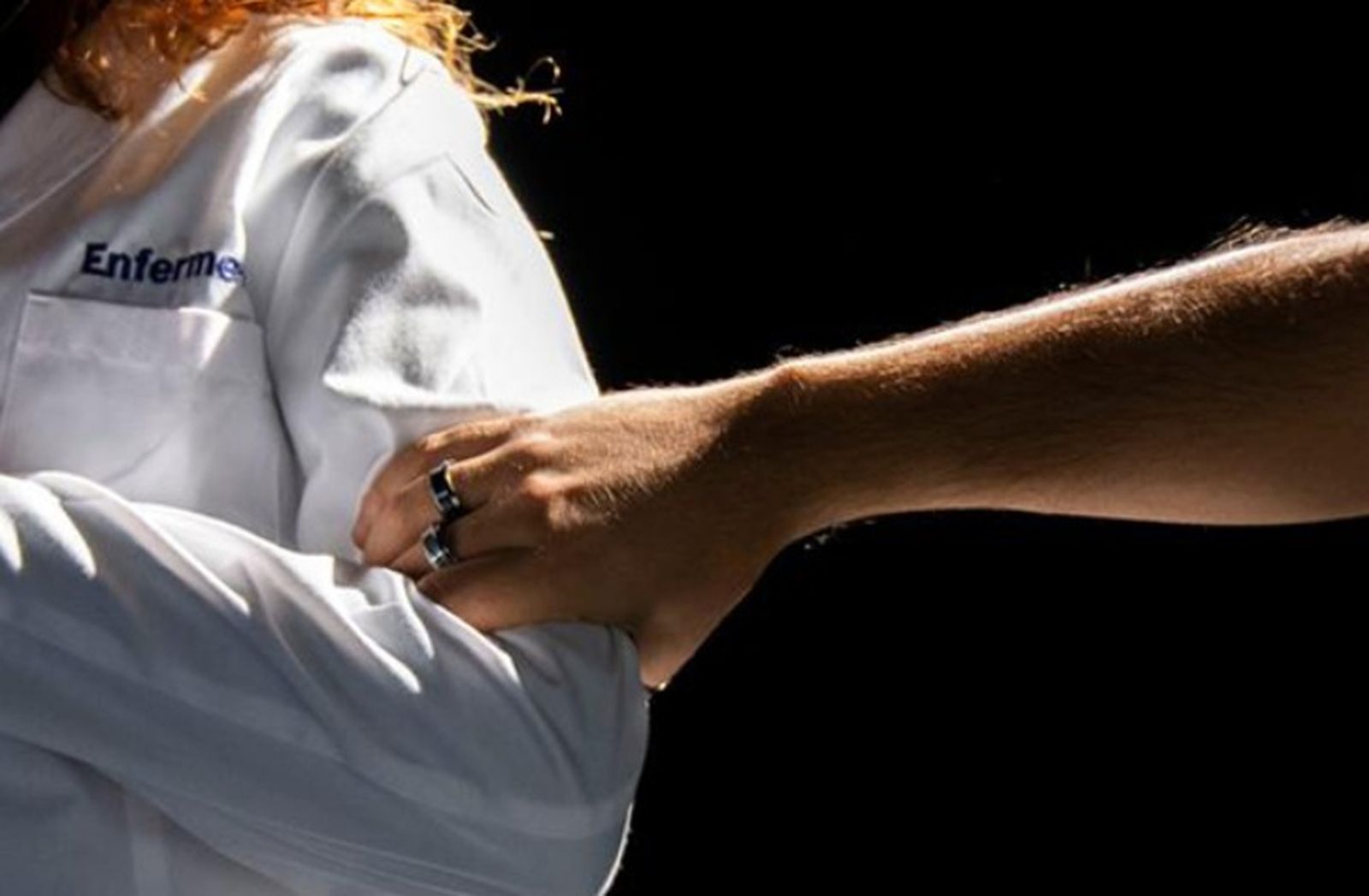 Una profesional de la enfermería mientras una persona le agarra del brazo en una imagen de archivo