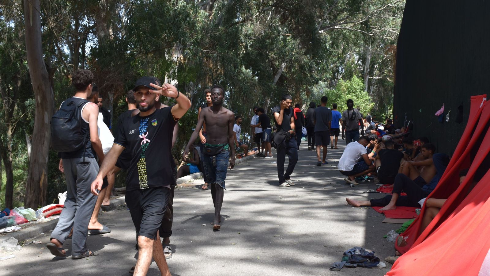 Migrantes en las inmediaciones del CETI a la espera de ingresar en las instalaciones, este jueves