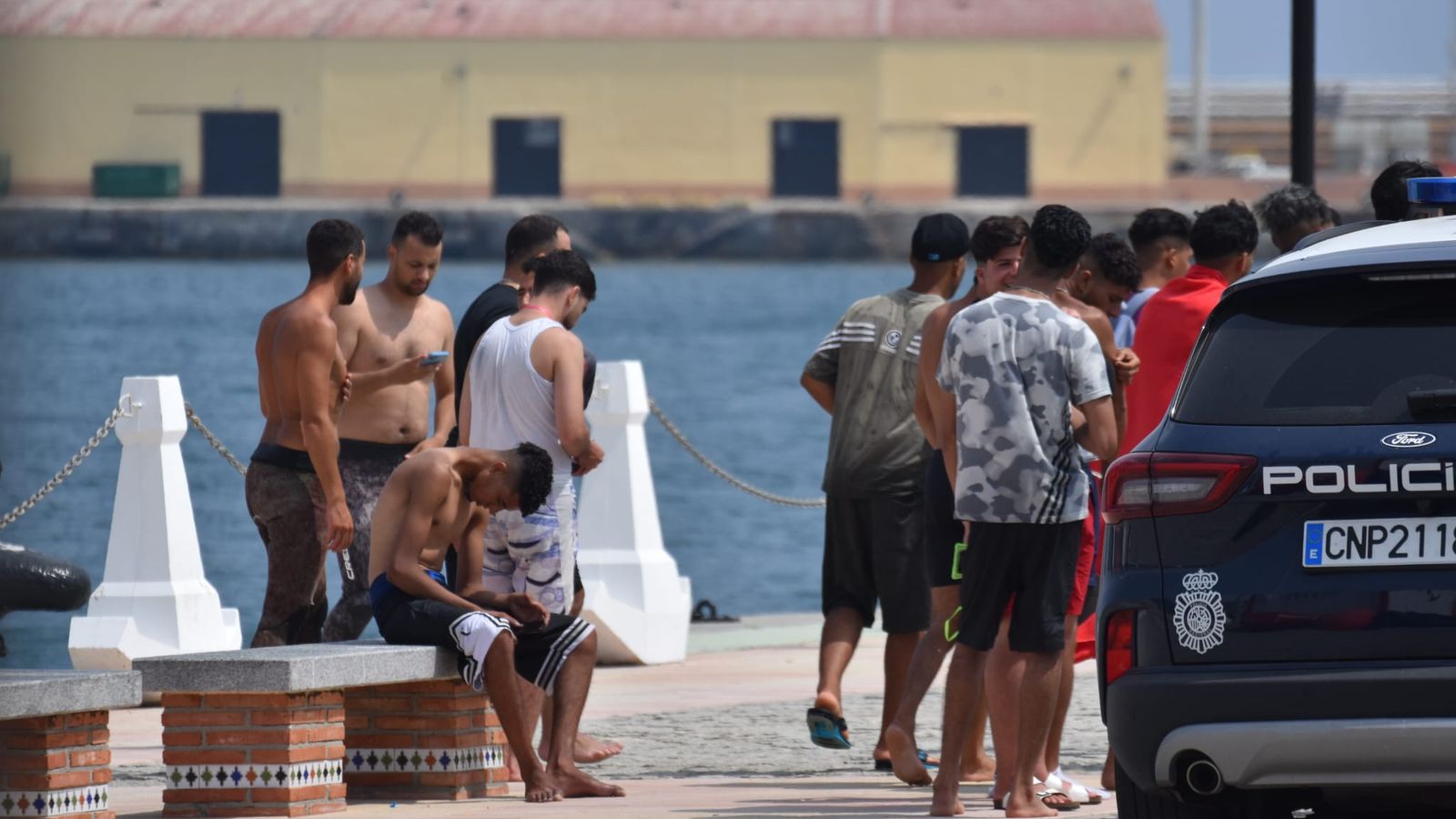 Varias personas magrebíes junto a efectivos policiales en el Muelle España, tras ser rescatados por Salvamento Marítimo
