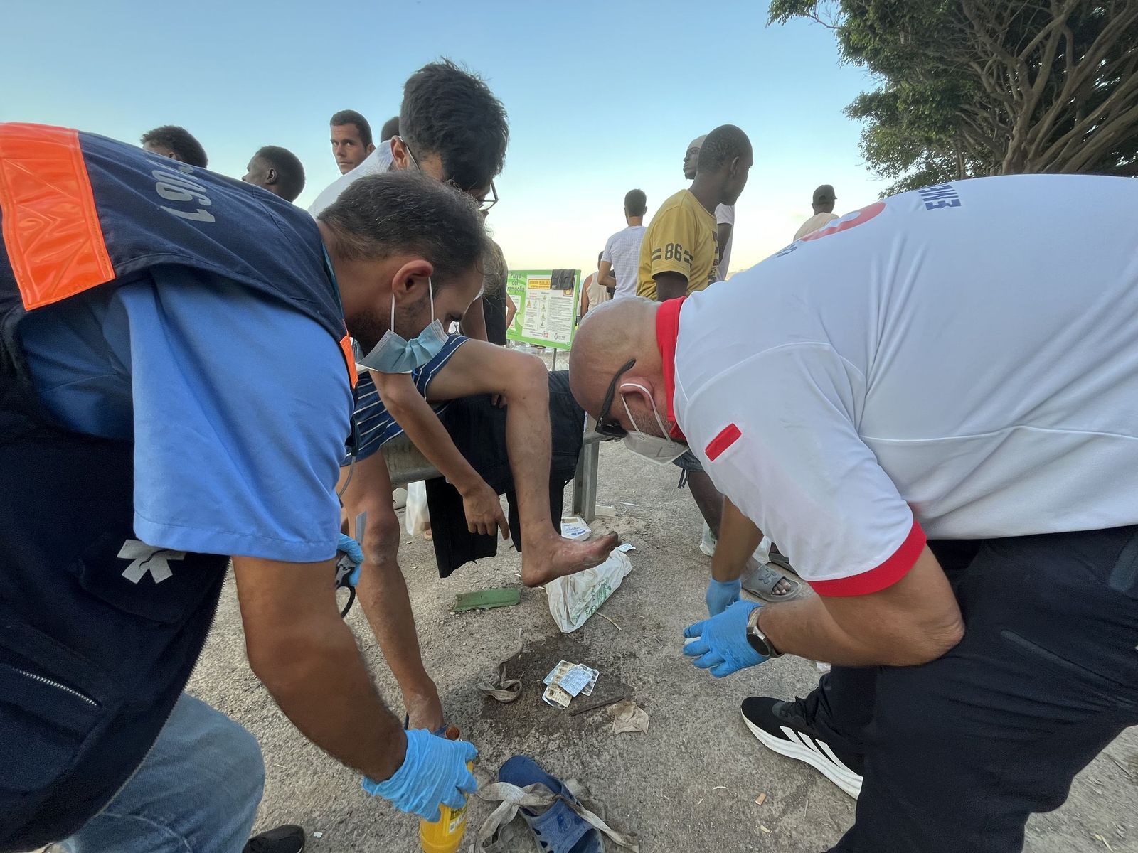 Un médico y un enfermero del INGESA atienden a un joven migrante en la playa del Trampolín