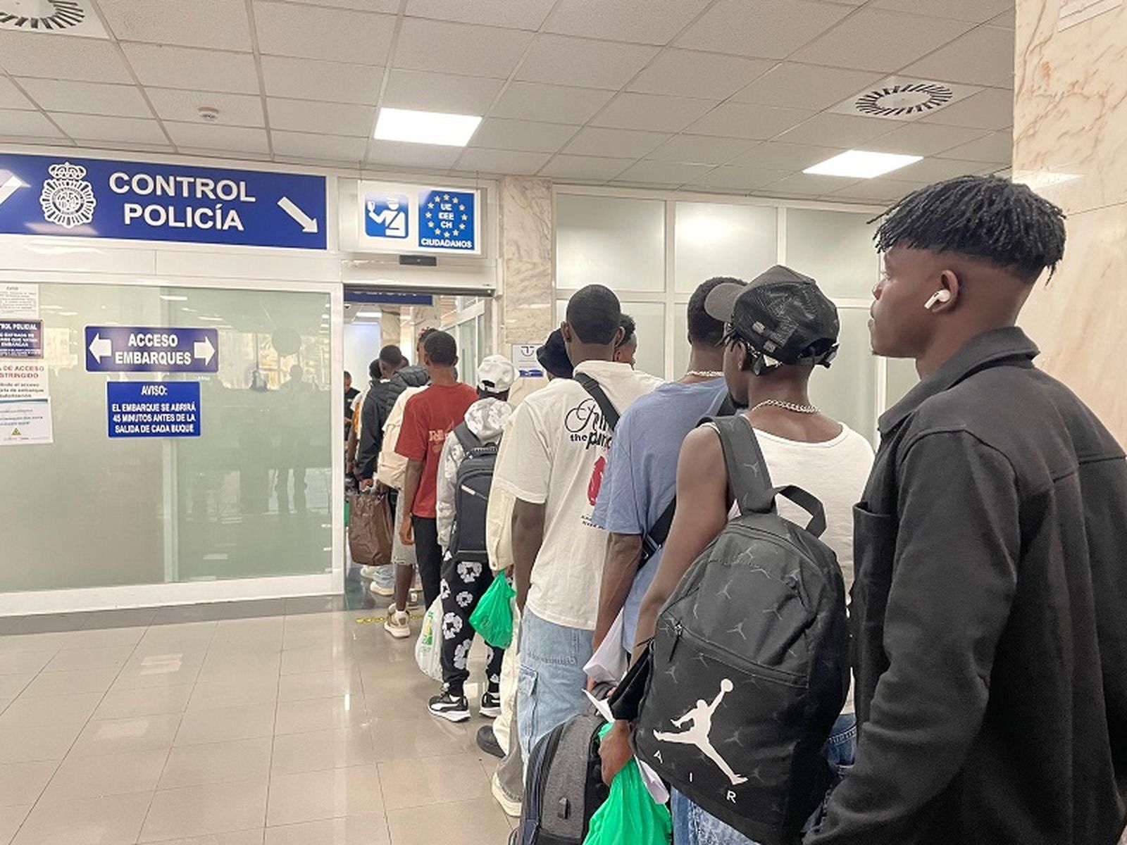 Un grupo de migrantes espera para pasar al control policial de la Estación Marítima de Ceuta