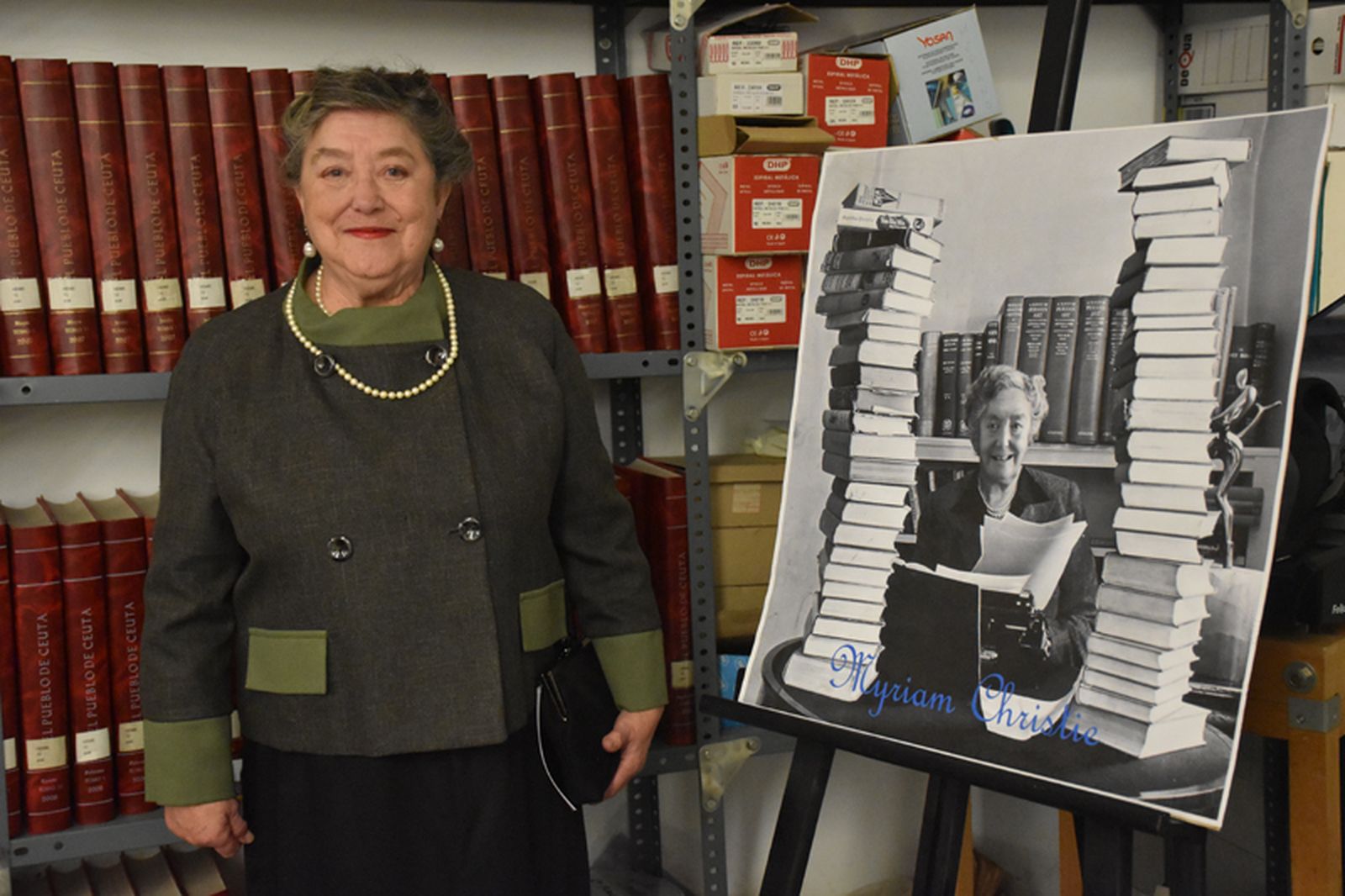 La señora Christie posa junto a una imagen suya y delante de varios ejemplares antiguos de El Pueblo de Ceuta en la Biblioteca Pública. / FOTO G.S.