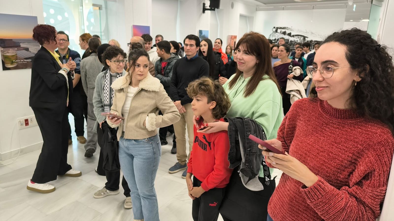 Asistentes al acto de inauguración de la muestra contemplan los trabajos expuestos