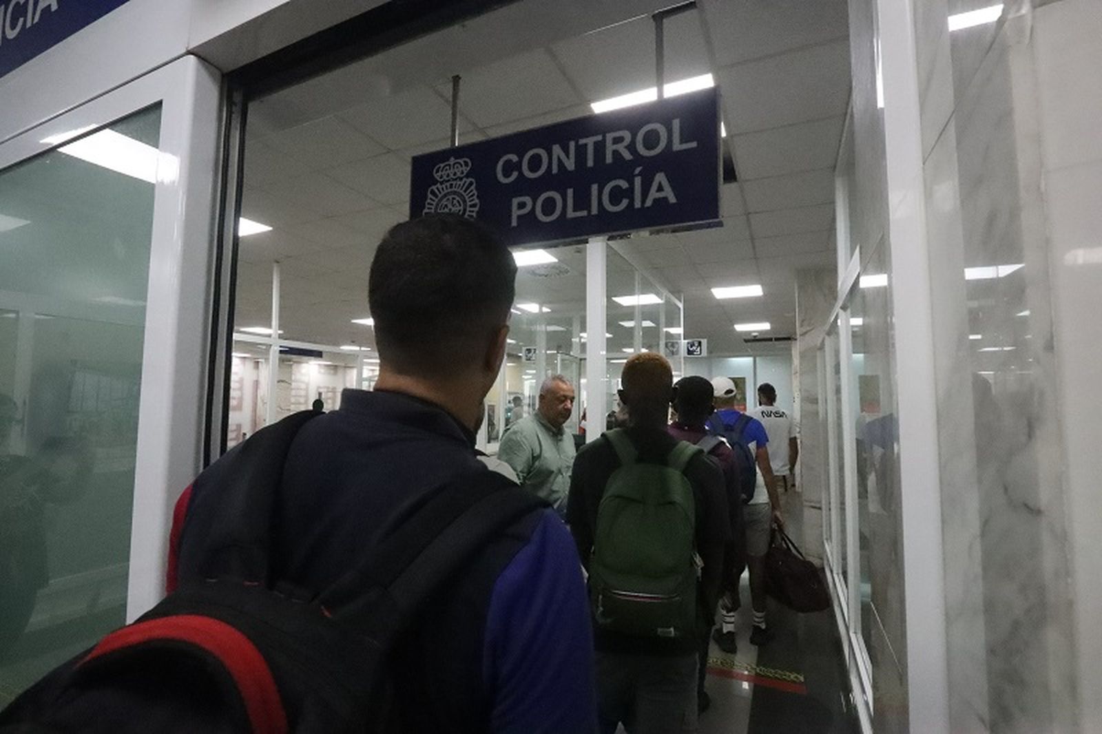 Varios migrantes cruzan la puerta de embarque de la Estación Marítima de Ceuta. / FOTO REDUAN