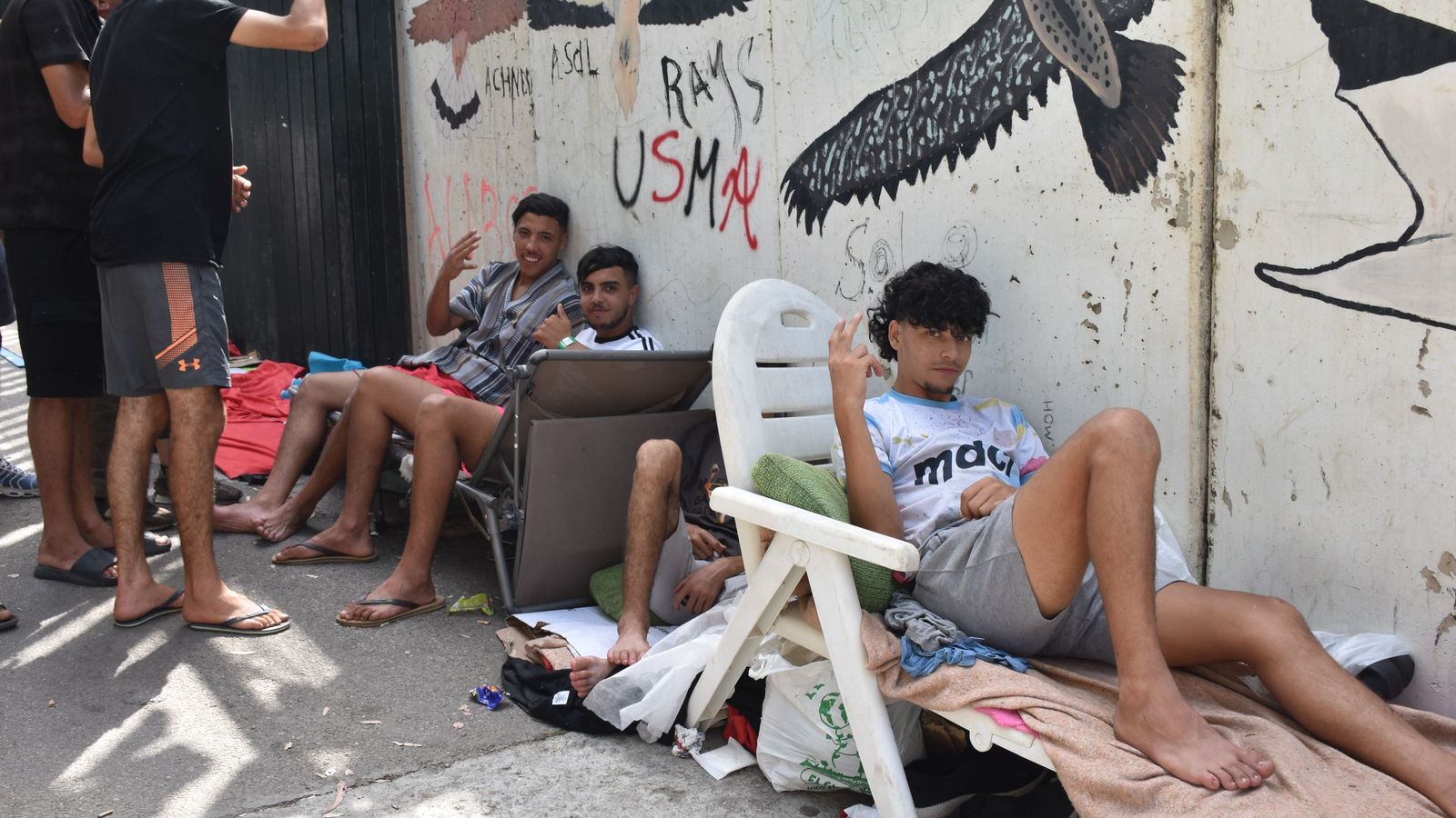 Migrantes en las inmediaciones del CETI a la espera de ingresar en las instalaciones, este jueves