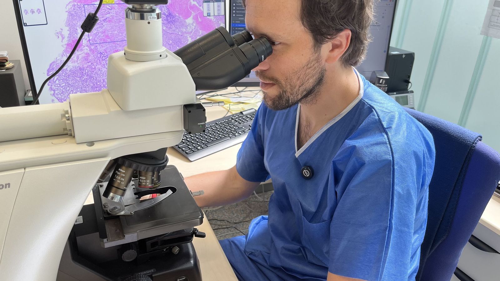 El patólogo Nicolás López mira por el microscopio de su compañera, Pilar Bados. En la pantalla del ordenador, la imagen de alta resolución de una muestra biológica digitalizada gracias al escáner de portaobjetos adquirido por INGESA