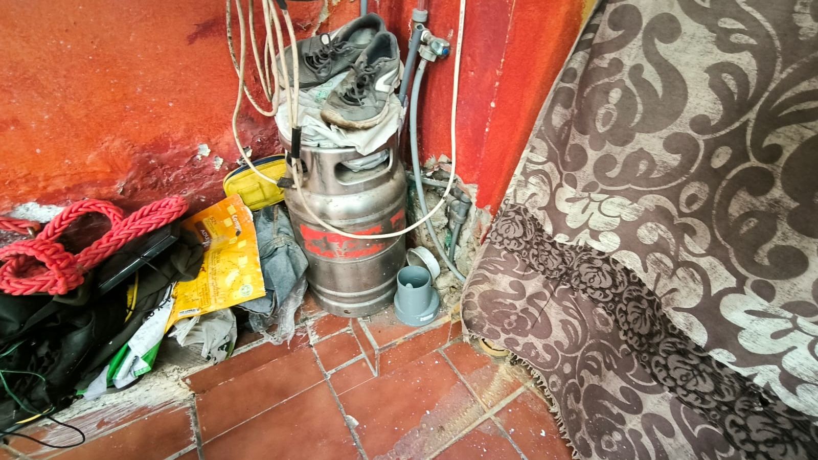 Entrada de la casa, con la pared desconchada y tuberías a la vista.