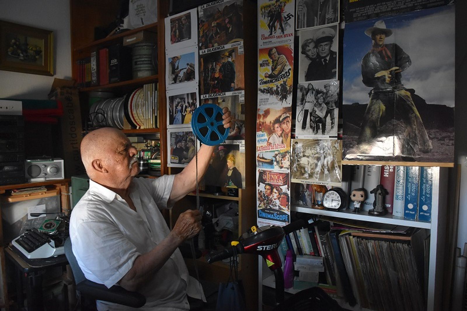 Ricardo Teresa posa sosteniendo uno de los carretes de su colección de películas antiguas en la "sala del cine" de su casa.