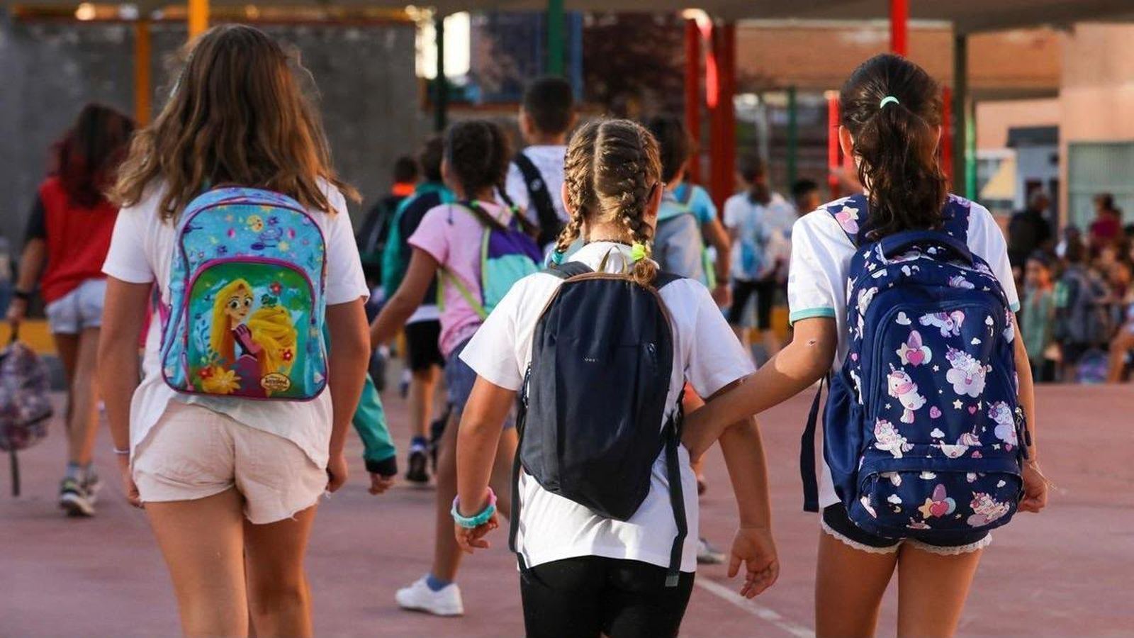 Alumnos portando las mochilas con los libros