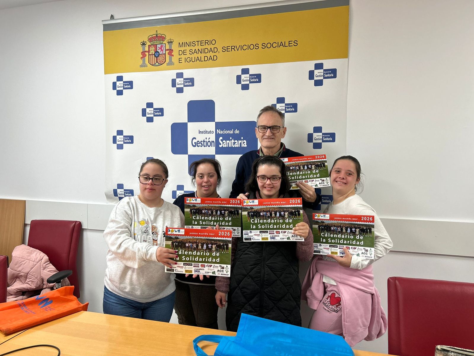 El director territorial del INGESA, Jesús Lopera, posa junto a representantes de Síndrome de Down Ceuta con el calendario solidario