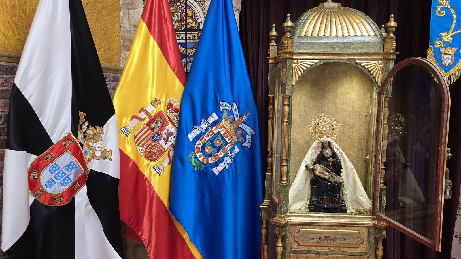 Imagen de la Virgen en la Casa de Ceuta en Melilla junto a banderas de Ceuta, España y Melilla
