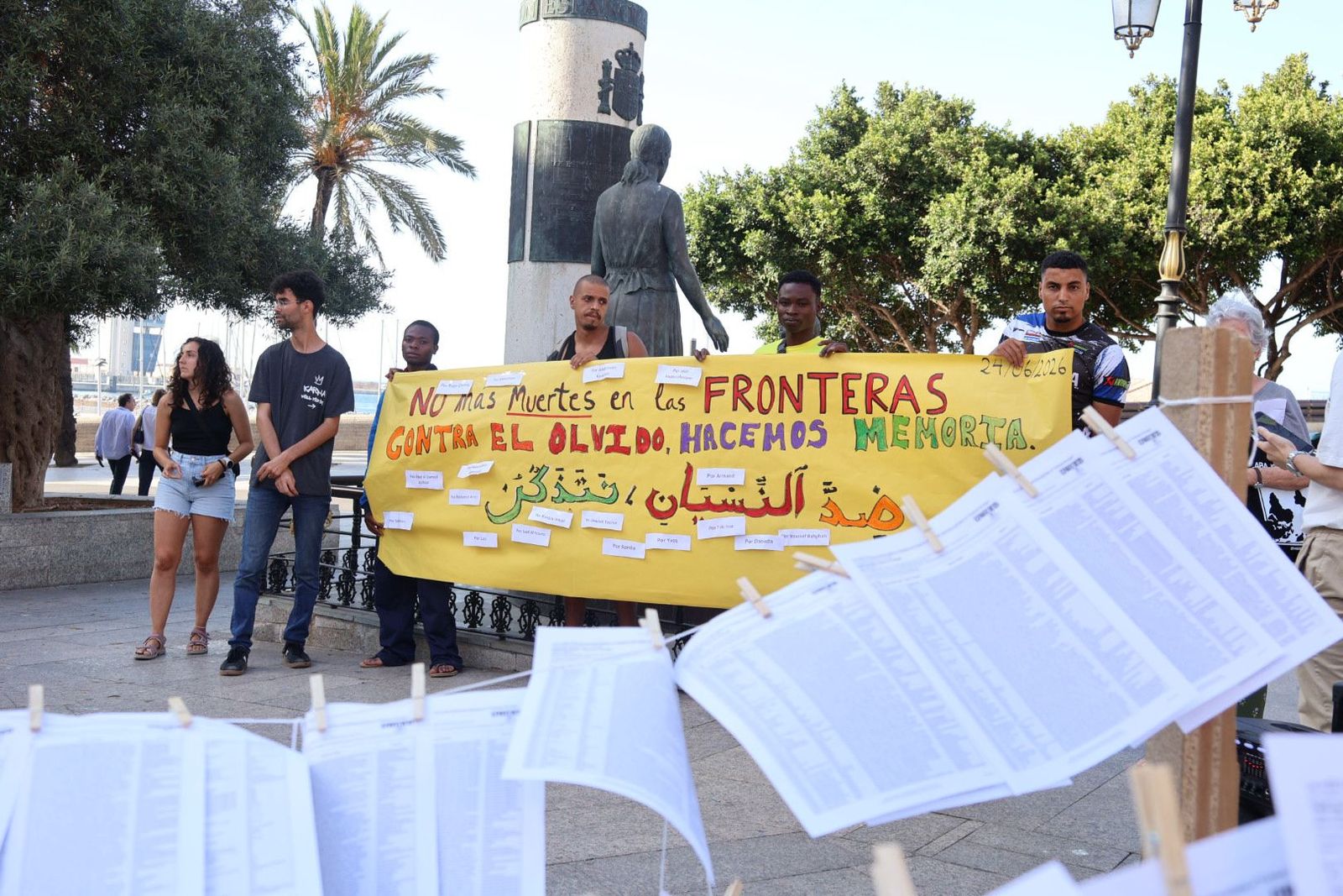 Migrantes sujetando una pancarta y los folios de los más de 60.000 fallecidos en Europa desde 1993