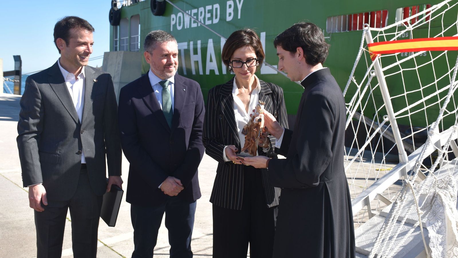 El sacerdote ofrece a Emanuela Franchini, de Fratelli Cosulich, la imagen de la virgen del Carmen que protegerá la gabarra