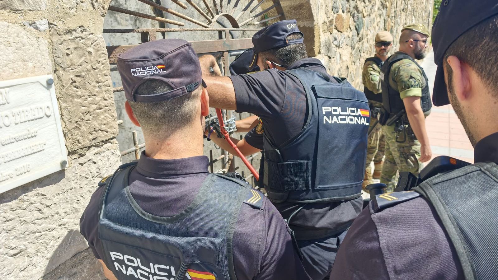 La Policía Nacional abre la puerta que conduce al antiguo gimnasio de Los Delfines, en el foso de las Murallas, donde se habían escondido los migrantes