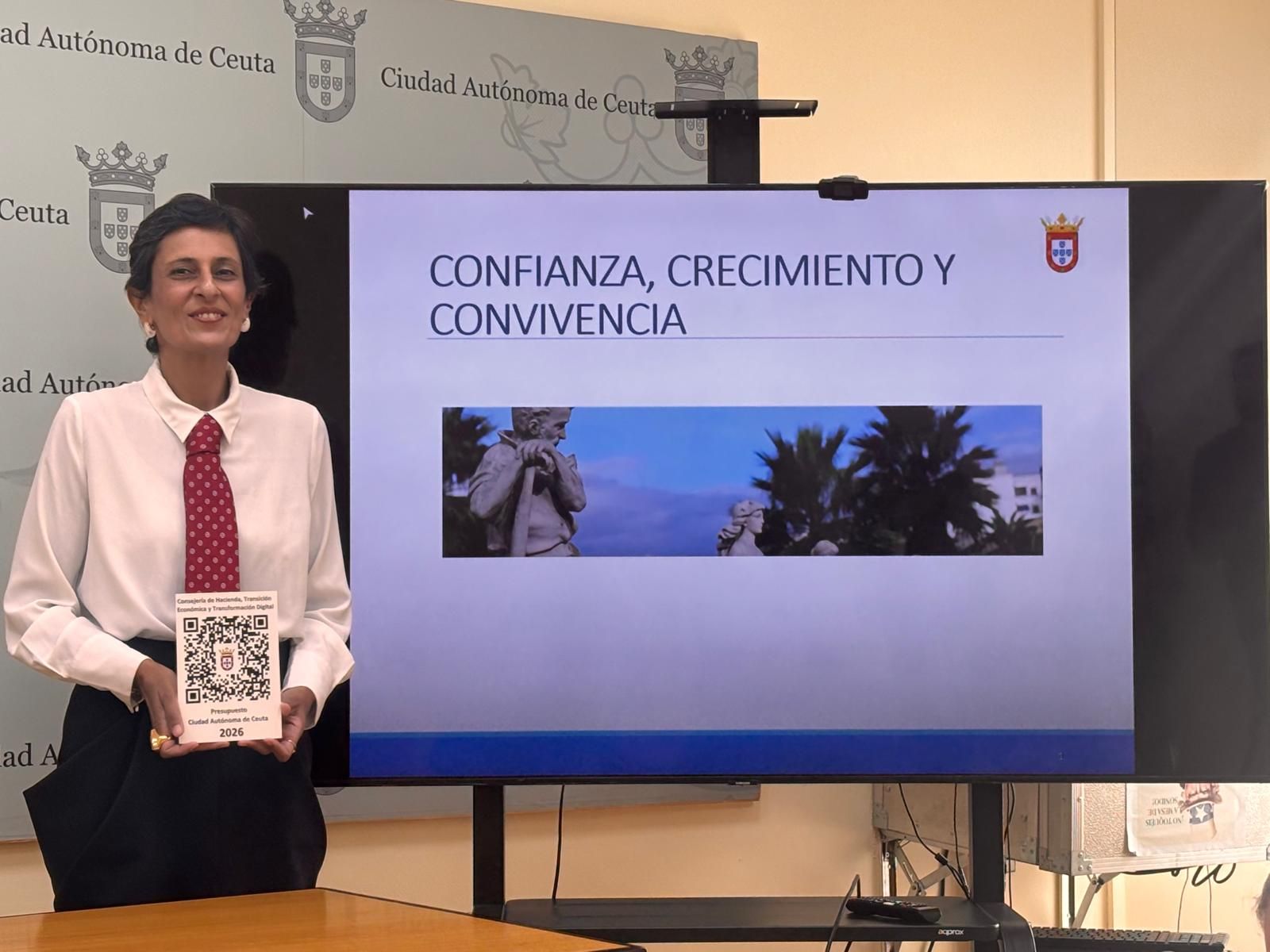 La consejera de Hacienda, Kissy Chandiramani, enseñando el QR con los Presupuestos provisionales para Ceuta 2026.